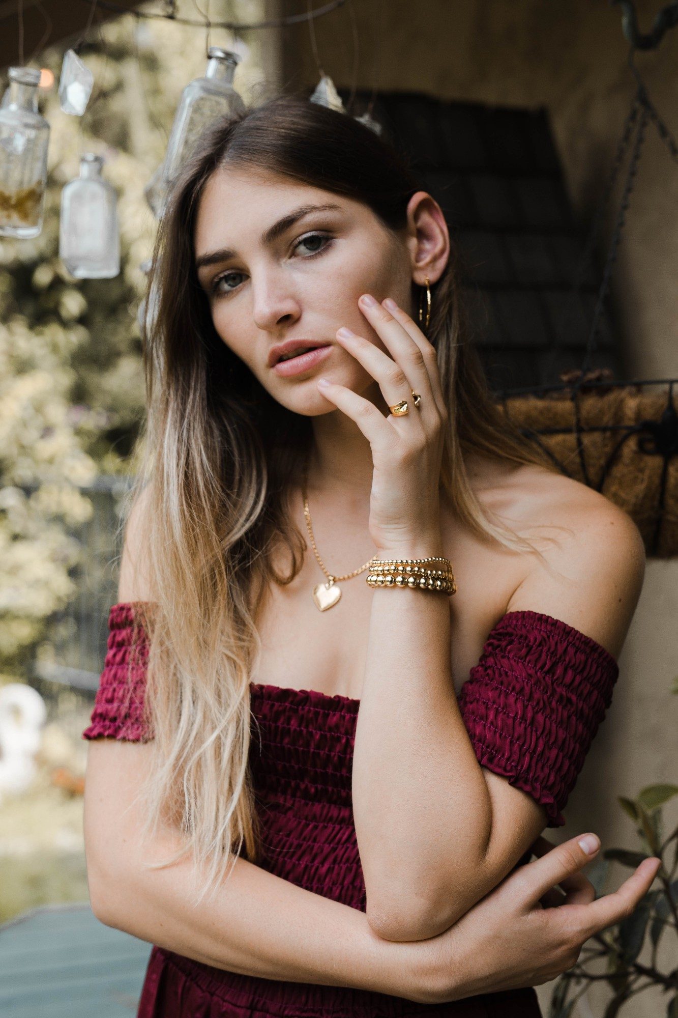 Close-up portrait showing gold rings, beaded bracelets and a heart pendant